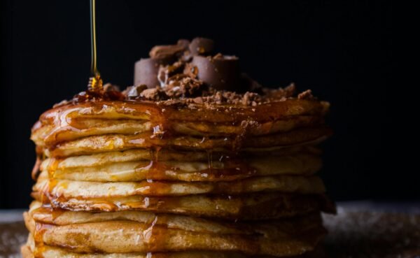 Mouthwatering stack of pancakes topped with chocolate and syrup. Perfect breakfast delight.